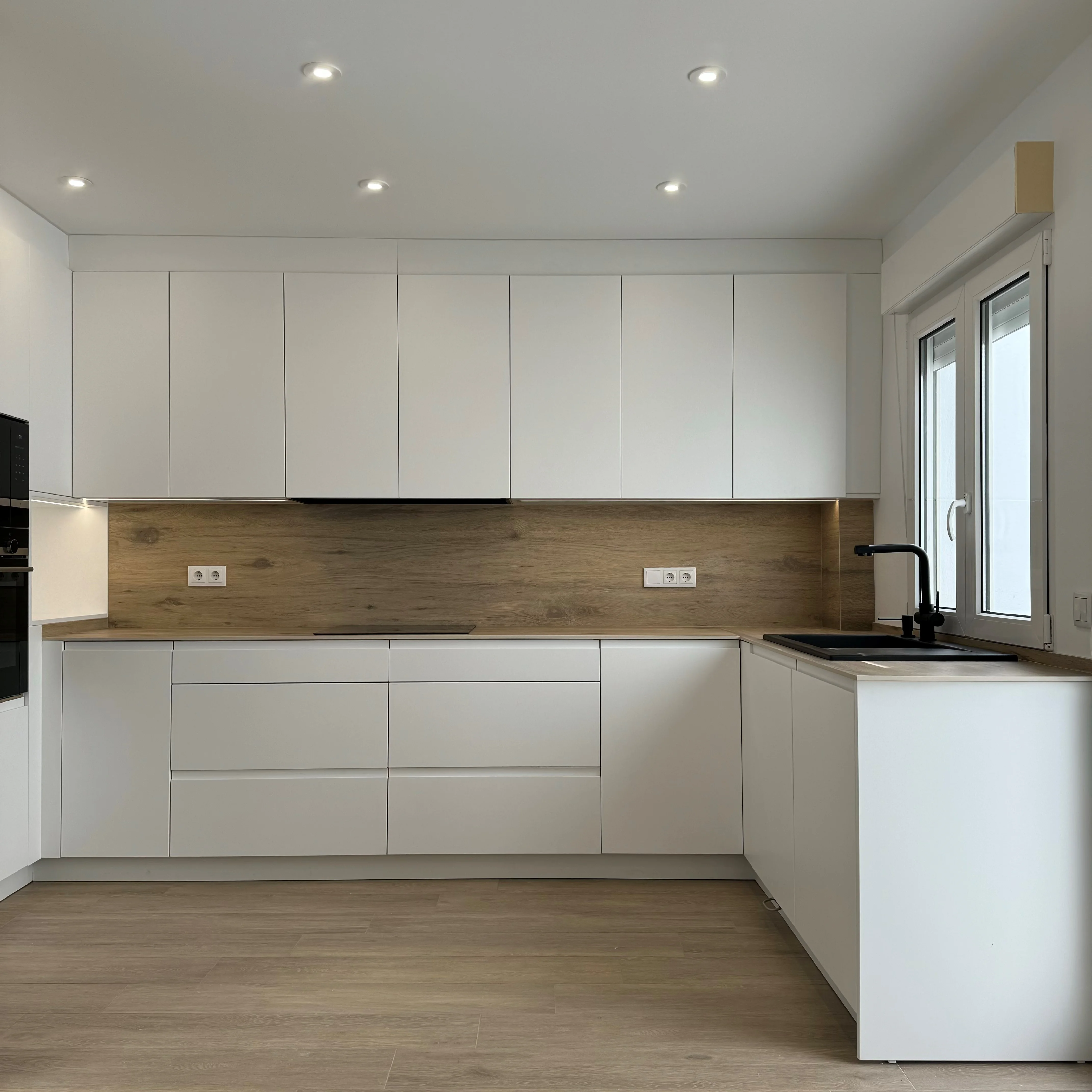 Cocina sin tirador blanca mate con veta de madera, diseño FingerPull de Masmoebel en Huelva